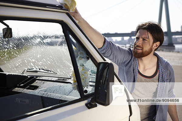 Man washing front window of a car