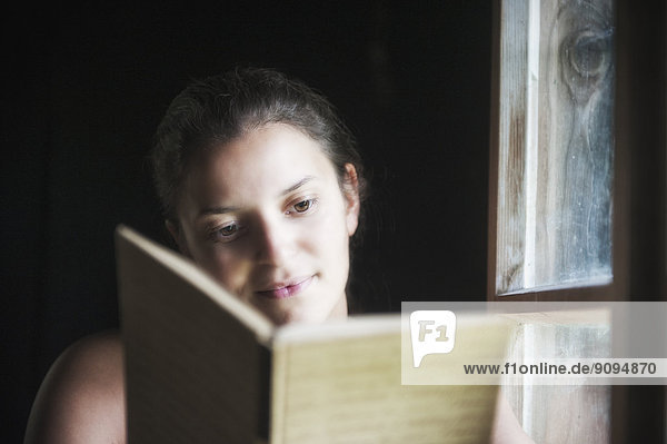 Young woman reading a book  at the window