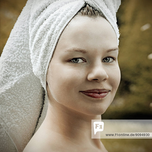 Porträt einer lächelnden Frau mit Handtuch auf dem Kopf