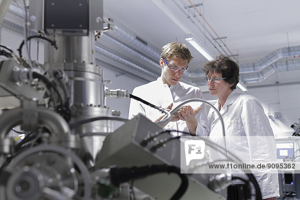 Zwei Wissenschaftler im analytischen Labor mit Rasterelektronenmikroskop im Vordergrund