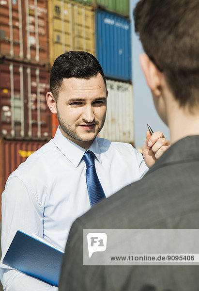 Porträt eines Geschäftsmannes im Gespräch mit einem Teenager am Containerterminal