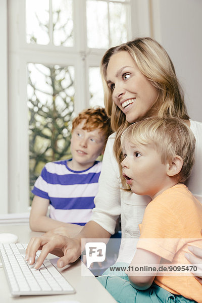 Happy mother with two sons looking at computer screen
