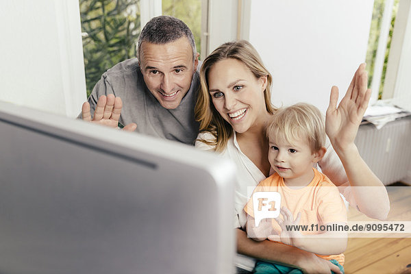 Glücklicher Großvater  Mutter und Sohn winken am Computerbildschirm