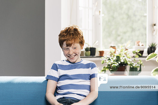 Junge sitzend auf blauer Couch im Wohnzimmer