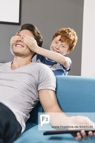 Boy covering eyes of his father