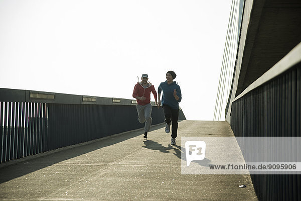 Junger Mann und Teenager laufen auf der Brücke