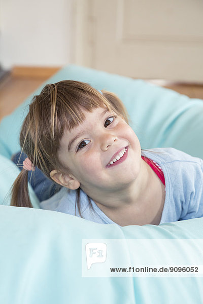 Porträt eines lächelnden kleinen Mädchens auf einem Bohnensack liegend