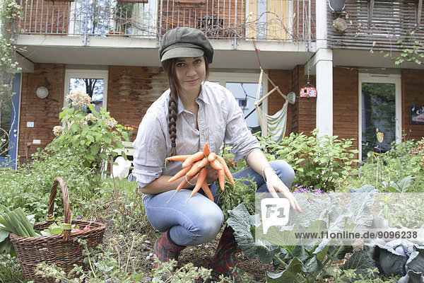 Young woman with carrots in vegetable garden
