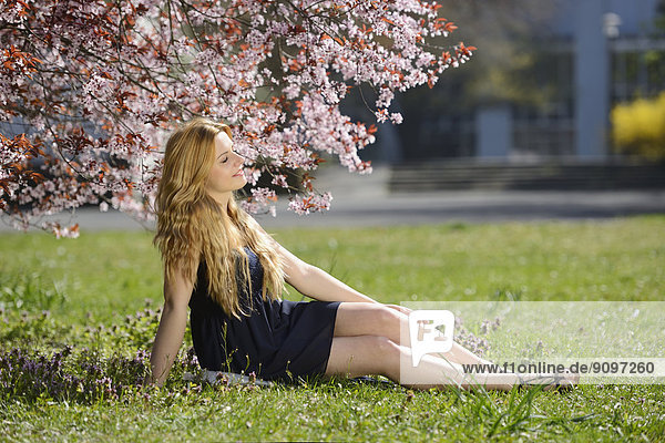 Junge Frau sitzt auf einer Wiese im Park