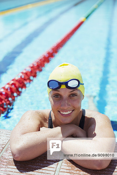 Porträt eines lächelnden Schwimmers  der sich am Beckenrand lehnt