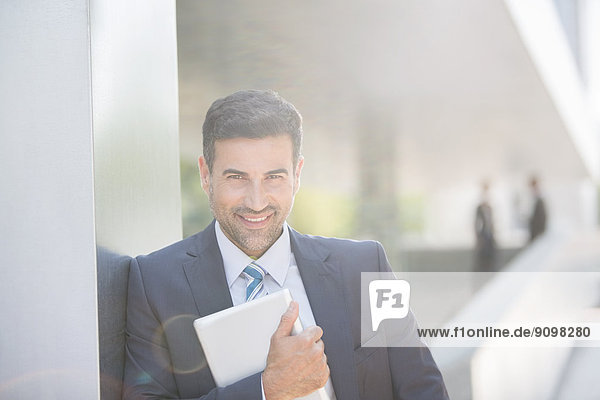 Portrait of confident businessman holding digital tablet outdoors