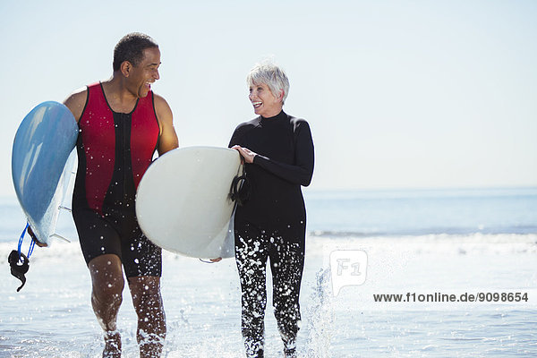 Seniorenpaar mit Surfbrettern am Strand
