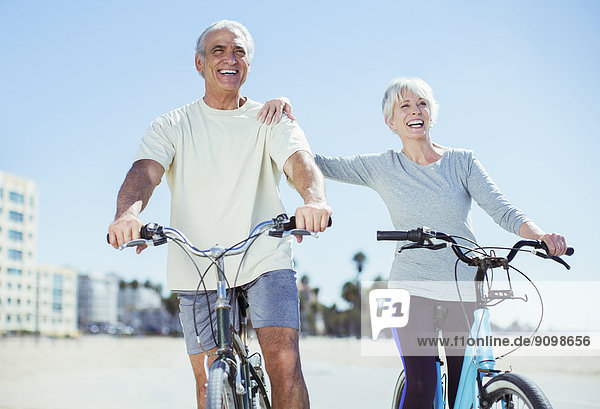 Seniorenpaar mit Fahrrädern am Strand