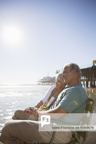 Senior couple relaxing in lawn chairs on beach