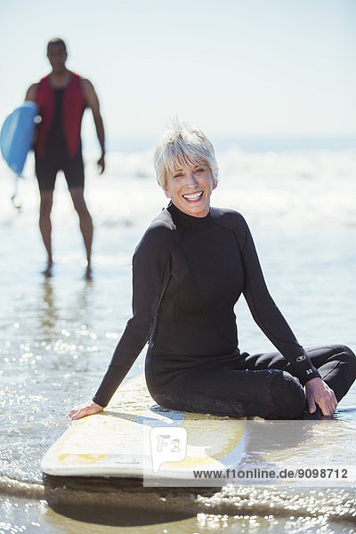 Porträt der Seniorin auf dem Surfbrett am Strand