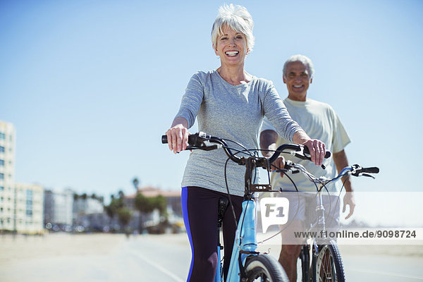 Portrait of senior couple with bicycles on beach boardwalk