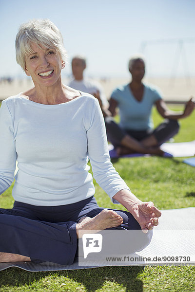 Porträt der lächelnden Seniorin beim Yoga im Park