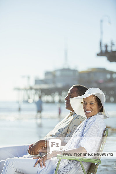 Porträt eines Paares in Liegestühlen am sonnigen Strand