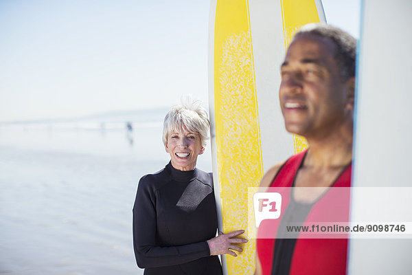 Portrait eines älteren Paares mit Surfbrettern am Strand