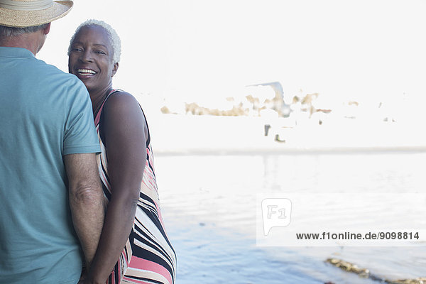 Porträt eines lächelnden Seniorenpaares am Strand