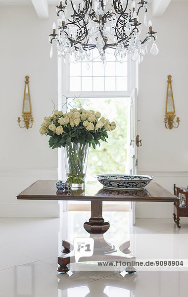 Kronleuchter über Blumenstrauß auf Tisch im luxuriösen Foyer