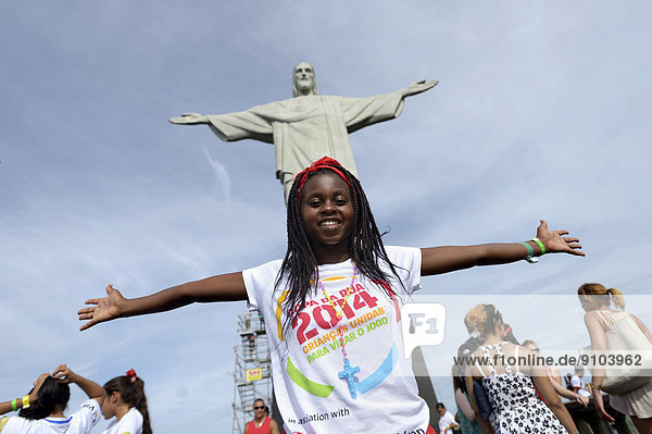 Young woman from Mozambique with her arms outstretched in front of the Christ the Redeemer statue  Cristo Redentor  on Corcovado Mountain  Rio de Janeiro  Rio de Janeiro State  Brazil
