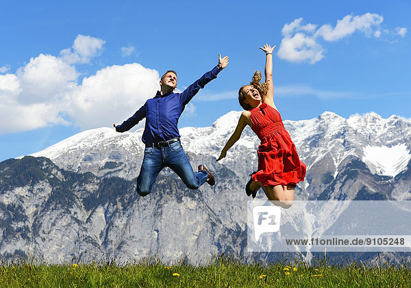 Mann und Frau springen im Frühling  hinten Berge  Tirol  Österreich