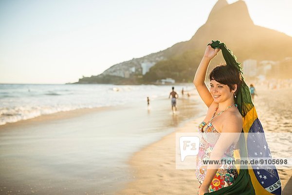 Young woman holding up Brazilian flag  Ipanema Beach  Rio  Brazil