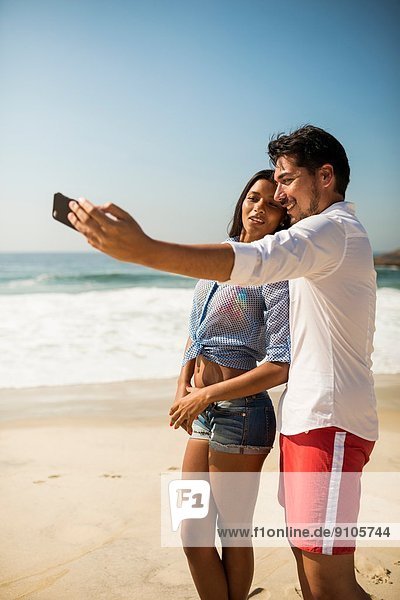 Couple taking self portrait on smartphone  Arpoador beach  Rio De Janeiro  Brazil