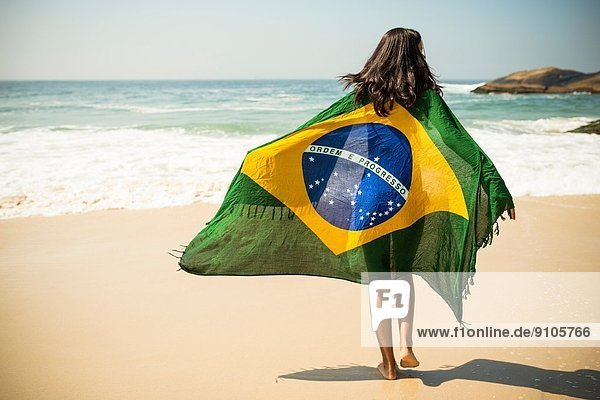Young woman wrapped in Brazilian flag  Arpoador beach  Rio De Janeiro  Brazil