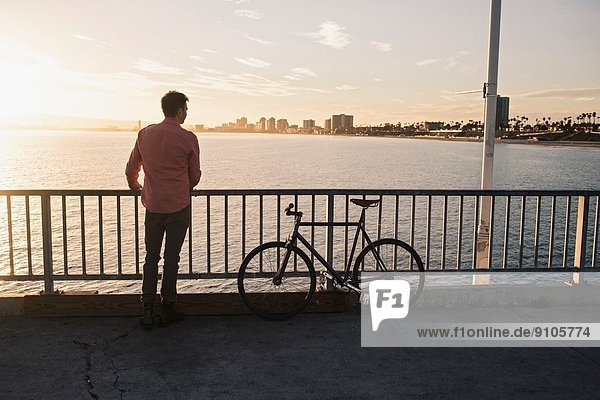 Young man gazing from pier  Long Beach  California  USA