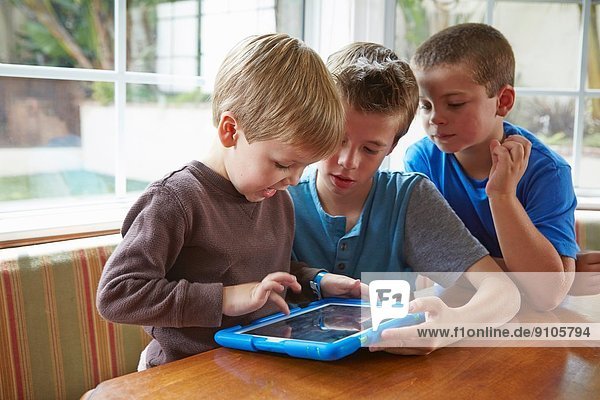 Drei Jungen spielen mit digitalem Tablett