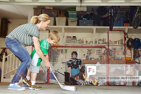 Mutter spielt Hockey in der Garage mit zwei Söhnen