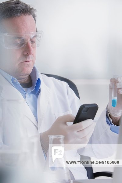 Wissenschaftler mit Smartphone und Reagenzglas