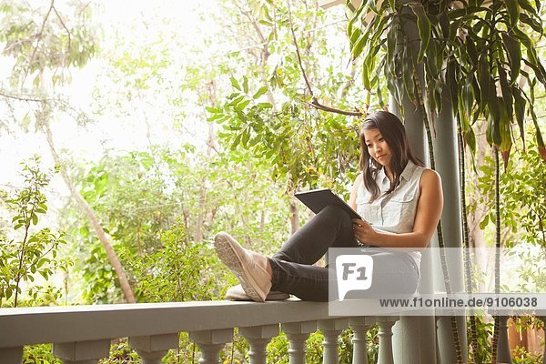 Junge Frau mit digitalem Tablett auf der Veranda