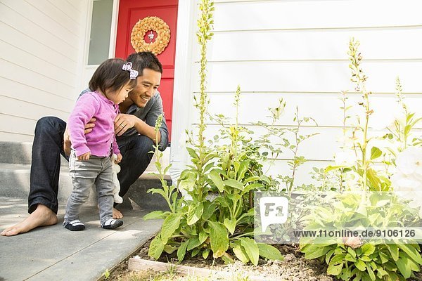 Mid adult man and toddler daughter looking at plants