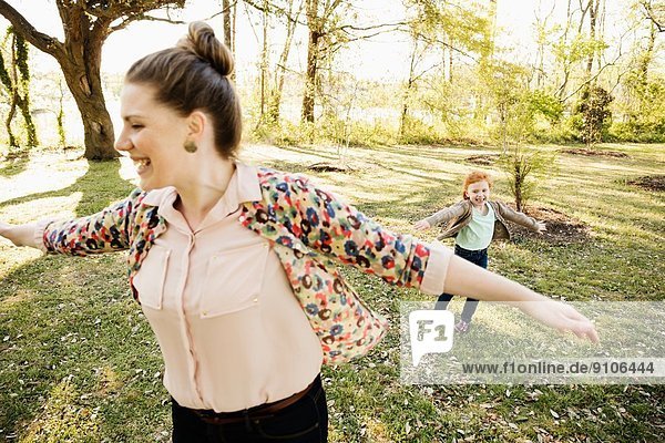 Mittlere erwachsene Mutter und Tochter beim Spielen auf Rasen im Park