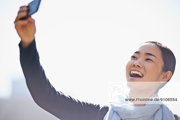 Junge Frau fotografiert sich mit dem Smartphone