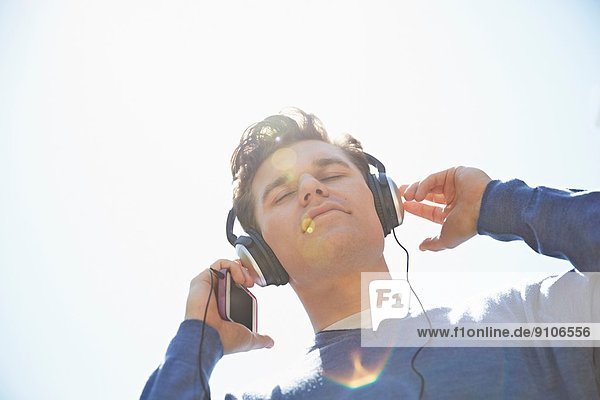 Junger Mann mit Kopfhörer beim Musikhören