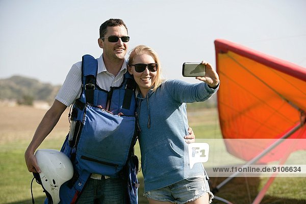 Couple taking selfie  hang glider in background