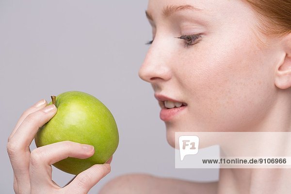 Porträt einer jungen Frau  die einen grünen Apfel hält