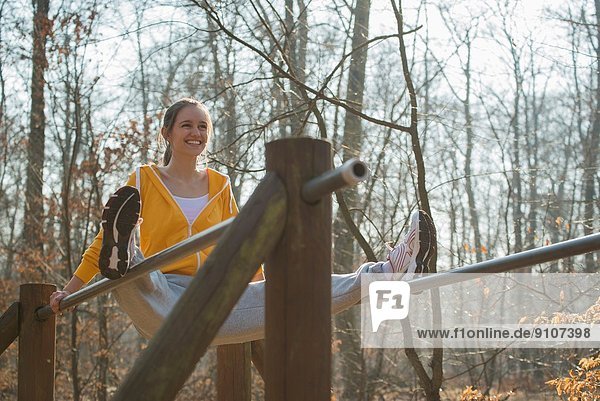 Junge Frau balanciert auf Barren auf Waldangriffsplatz