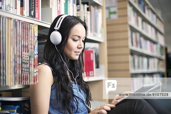 Junge Frau mit Kopfhörer und digitalem Tablett