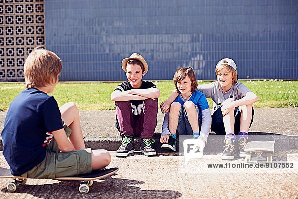 Jungen sitzen auf dem Bürgersteig mit Skateboards