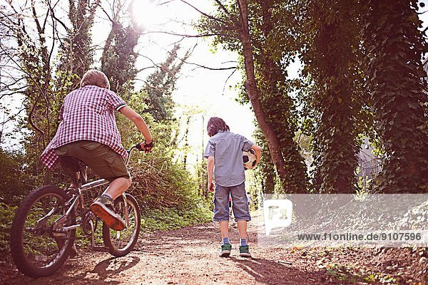 Junge auf Fahrrad mit Freund auf Waldweg