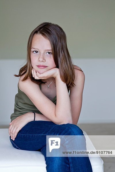 Porträt eines mürrischen zwölfjährigen Mädchens mit Hand am Kinn