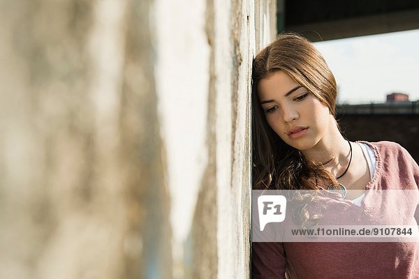 Young woman leaning against wall