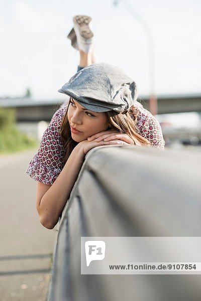 Young woman lying on front wearing flat cap