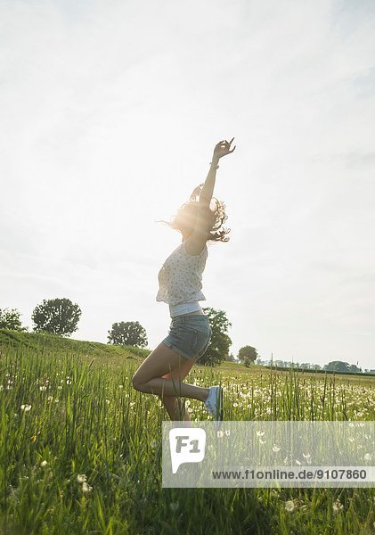 Young woman jumping in field