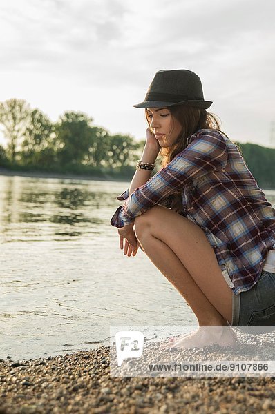 Young woman crouching by lake